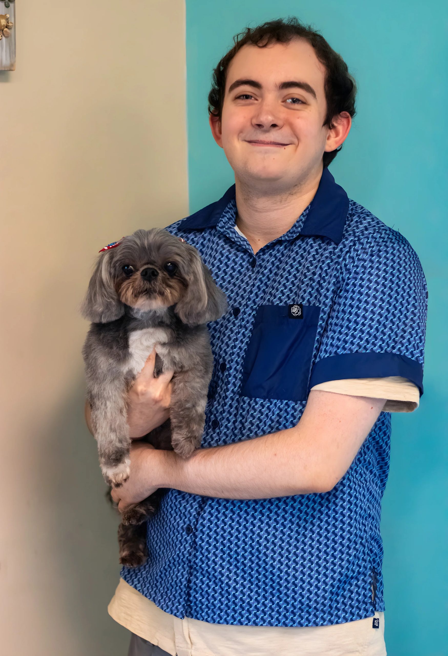 Smiling man holding grey Shih Tzu dog