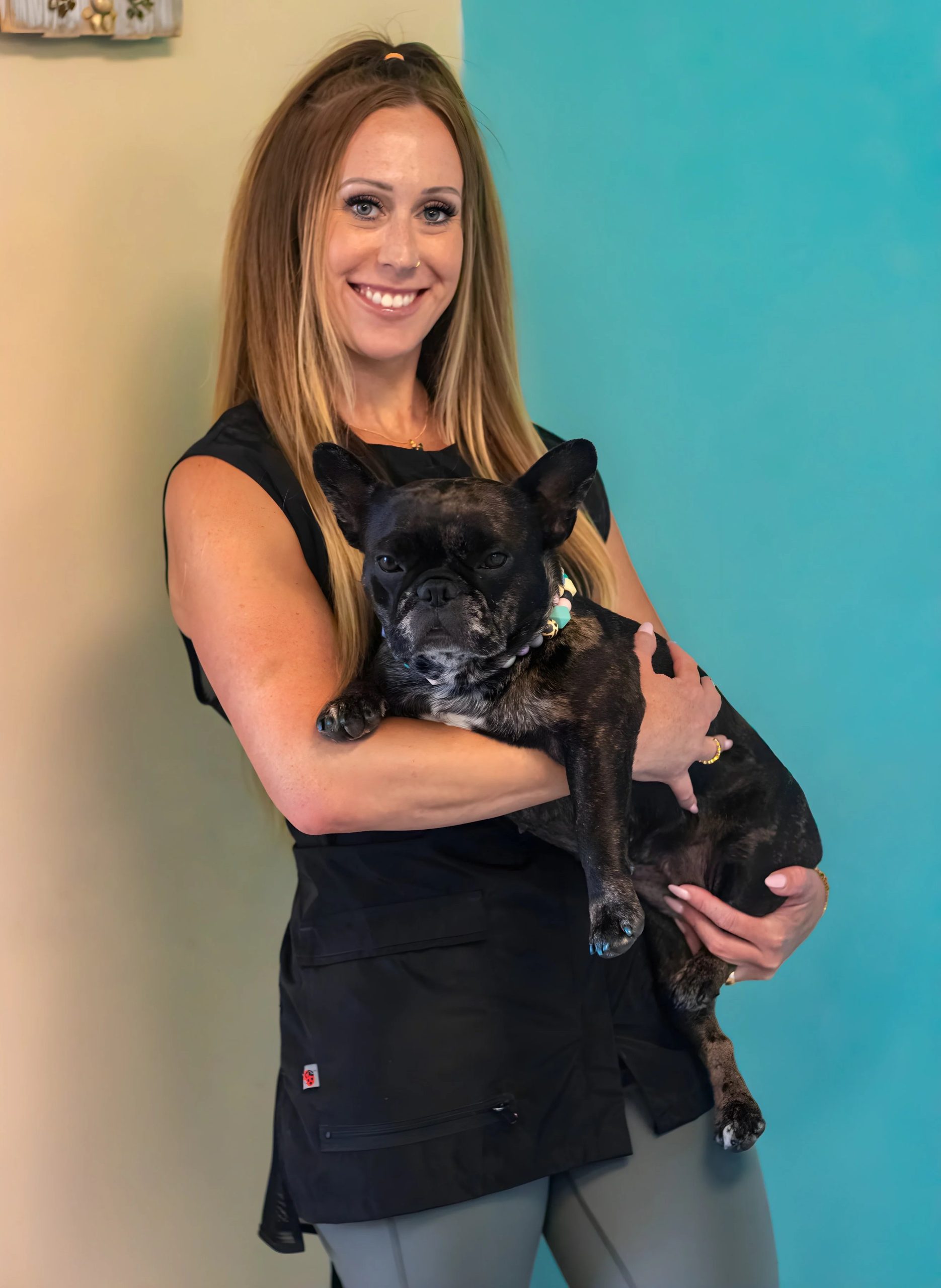 Smiling woman holding black French Bulldog