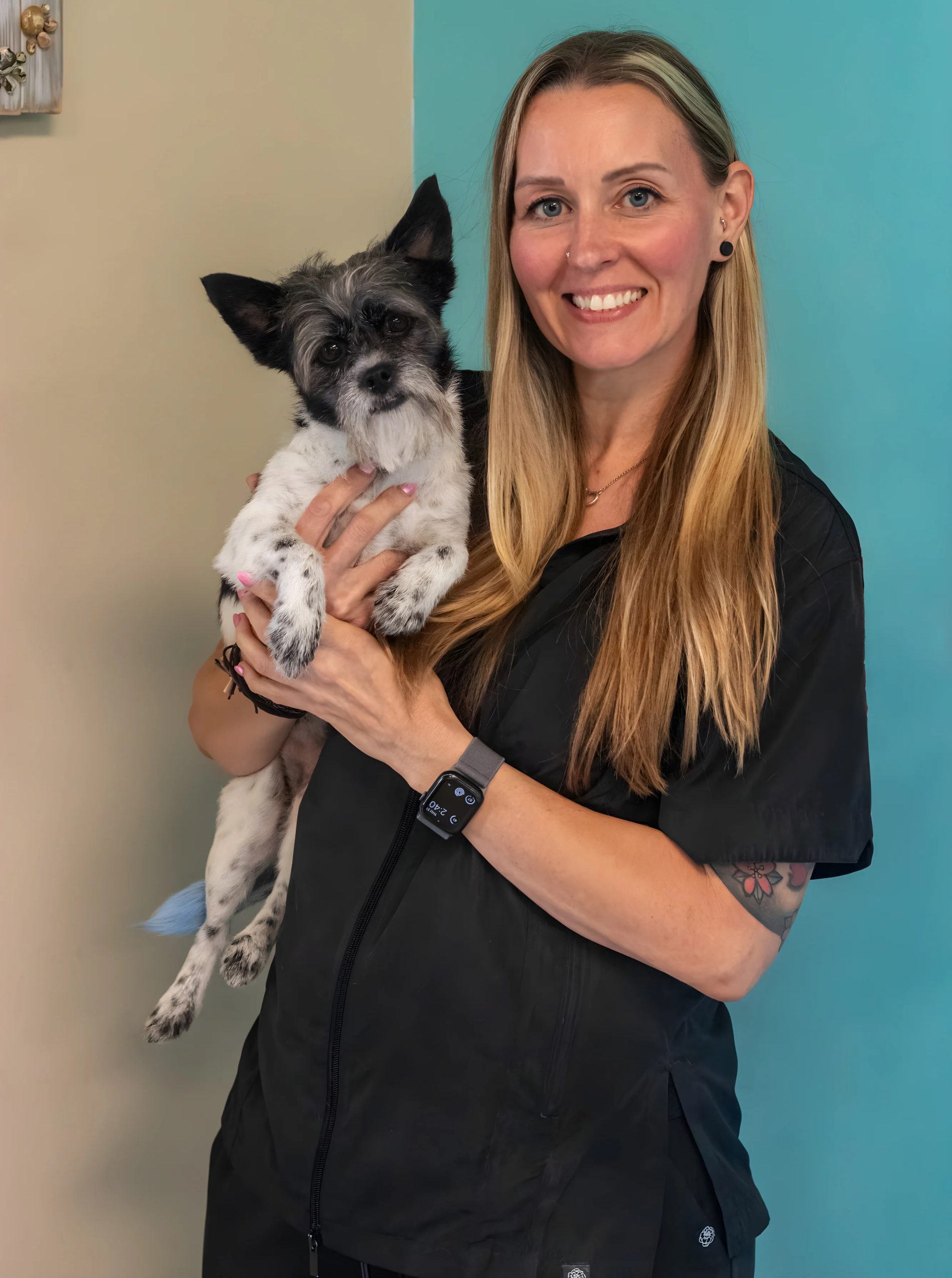 Smiling woman holding small black and white dog